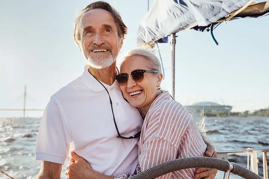 Pareja mayor abrazada en un barco, disfrutando de su jubilación con un plan preparado