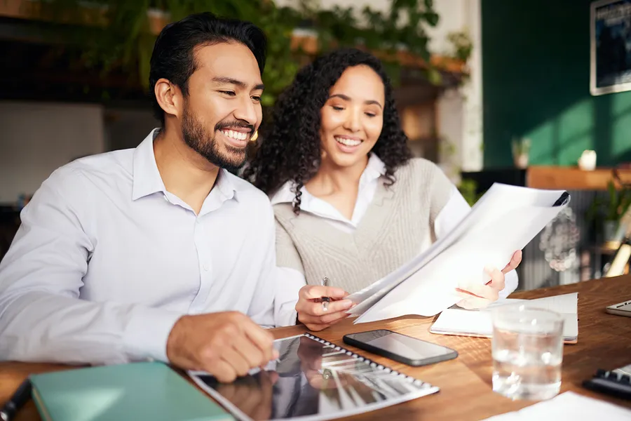 Dos personas repasando sobre la mesa el plan financiero que reciben por escrito